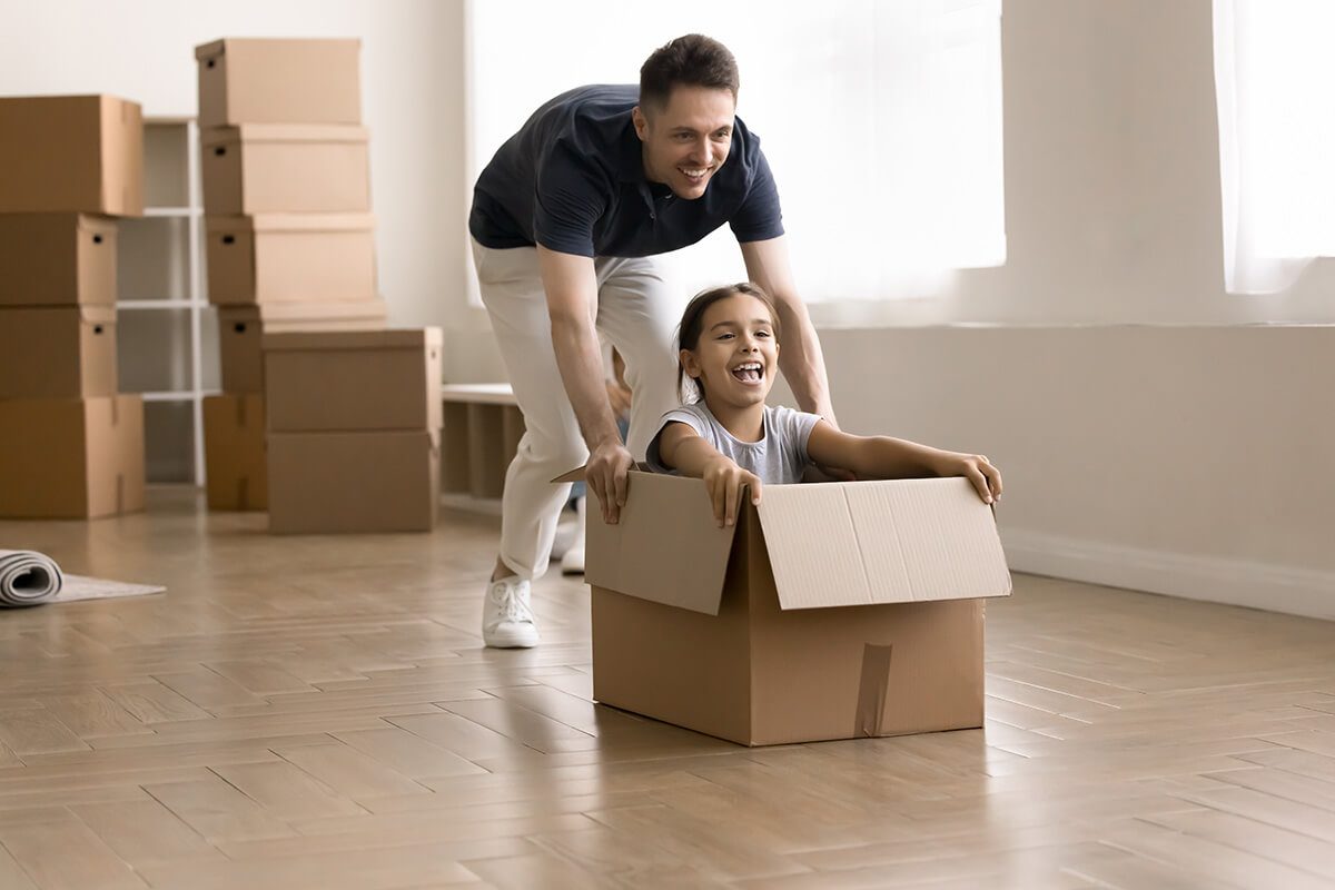 Young father riding his little daughter in box
