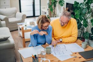 Senior couple sitting at table and looking into blueprints of their new home