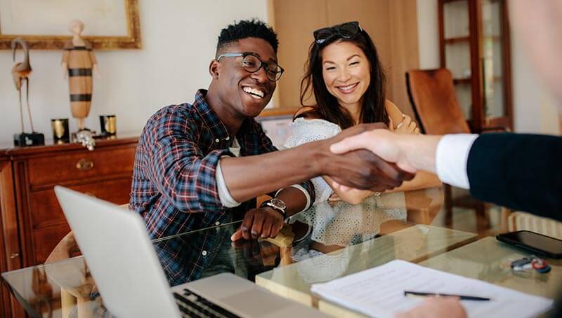 couple handshaking realtor after signing contract