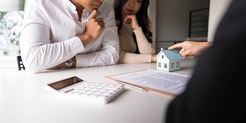 married couple sitting at table listening to realtor